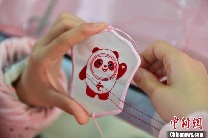 圖為一名小學(xué)生正在繡制2022年北京冬奧會(huì)吉祥物“冰墩墩”形象?！∮髟屏?攝