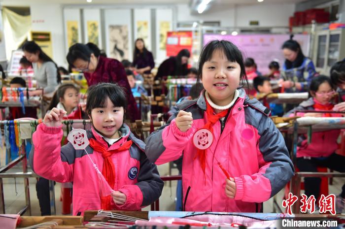圖為小學(xué)生展示繡制好的2022年北京冬奧會(huì)吉祥物“冰墩墩”形象?！∮髟屏?攝