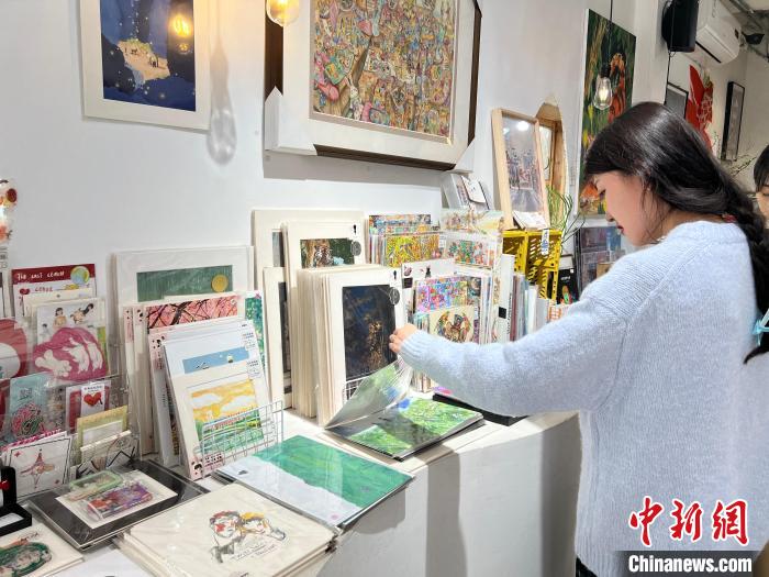 圖為藝術(shù)品商店內(nèi)，顧客挑選插畫作品。　鐘旖 攝