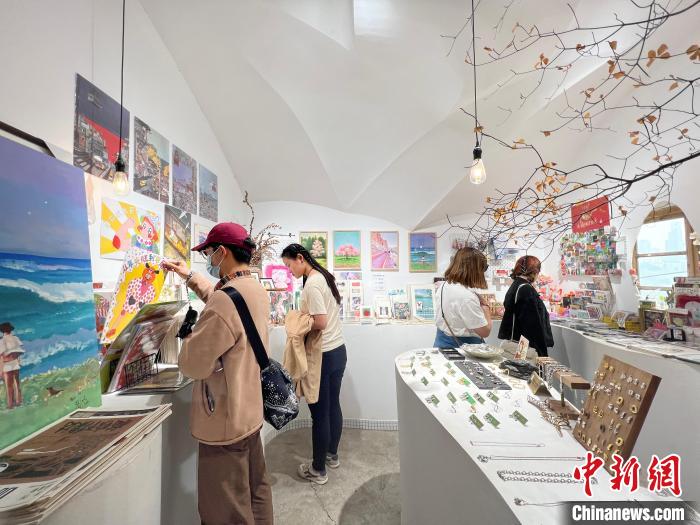 圖為藝術(shù)品商店內(nèi)，顧客挑選插畫作品?！＄婌?攝