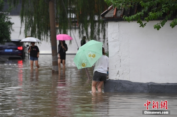 7月31日，市民行走在雨中的北京房山區(qū)瓦窯頭村。北京市氣象臺當(dāng)日10時發(fā)布分區(qū)域暴雨紅色預(yù)警信號。北京市水文總站發(fā)布洪水紅色預(yù)警，預(yù)計當(dāng)日12時至14時，房山區(qū)大石河流域?qū)⒊霈F(xiàn)紅色預(yù)警標(biāo)準(zhǔn)洪水。<a target='_blank' href='/'><p  align=