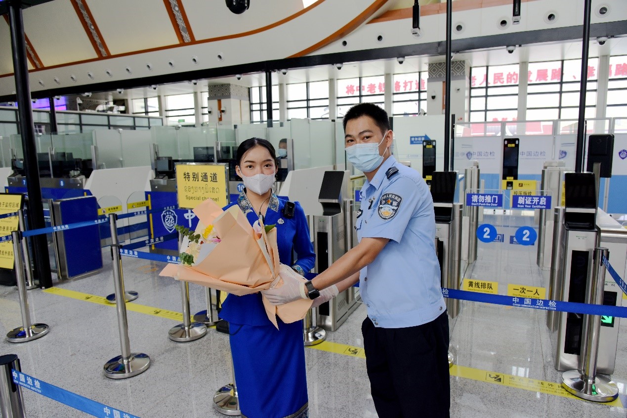 磨憨出入境邊防檢查站民警為中老鐵路第100萬名出入境旅客，D888次國際旅客列車?yán)蠐爰藙?wù)員森達(dá)拉·妮緹婭（Sengdala Nitiya），送上鮮花。黃遠(yuǎn)飛 攝