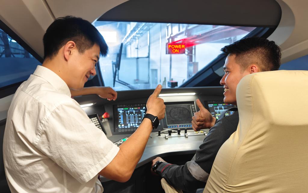 8月25日，在印度尼西亞萬隆的雅萬高鐵德卡魯爾動車所內，中國師傅穆振（左）在向印尼火車司機塞蒂亞萬講解動車組出庫前的上電作業(yè)。