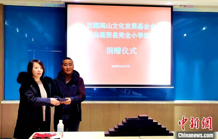 圖為西藏高山文化發(fā)展基金會(huì)理事長(zhǎng)溫麗向聶榮縣完全小學(xué)負(fù)責(zé)人捐助儀器?！∮谫e 攝