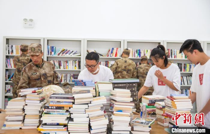 圖為志愿者們和邊防戰(zhàn)士整理圖書?！詵| 攝