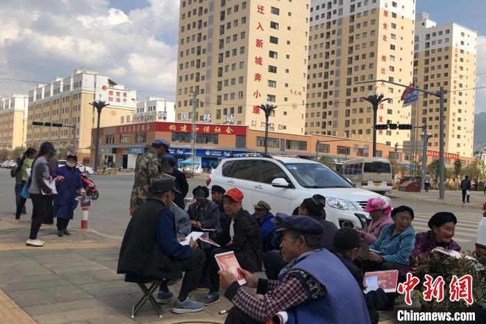 圖為會澤縣城易地扶貧搬遷安置點內，老人們聚在廣場上聊天，身后是他們的新家。　繆超 攝