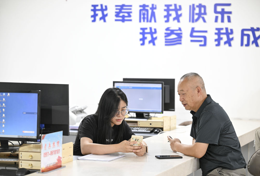 2024年6月20日，在寧夏銀川市金鳳區(qū)長城花園社區(qū)黨群服務(wù)中心，工作人員幫助居民辦理業(yè)務(wù)。圖片來源 新華社
