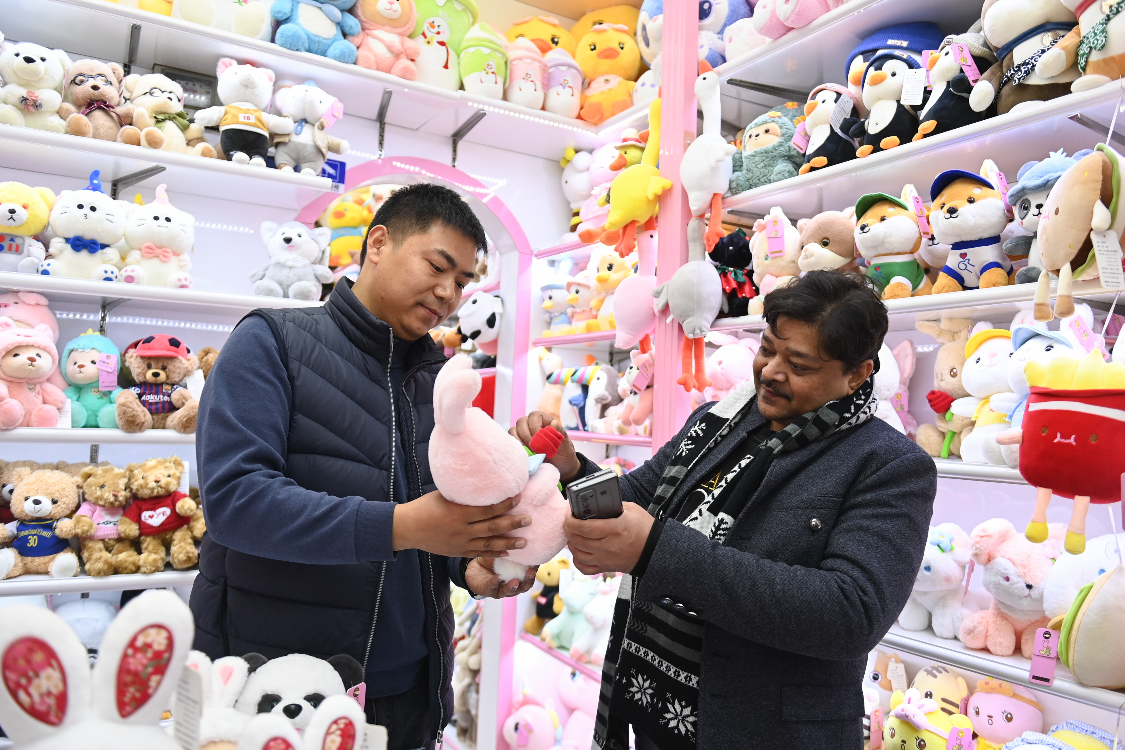 2023年2月2日，來自印度的客商（右）在義烏國際商貿城的一家玩具店鋪內選購。