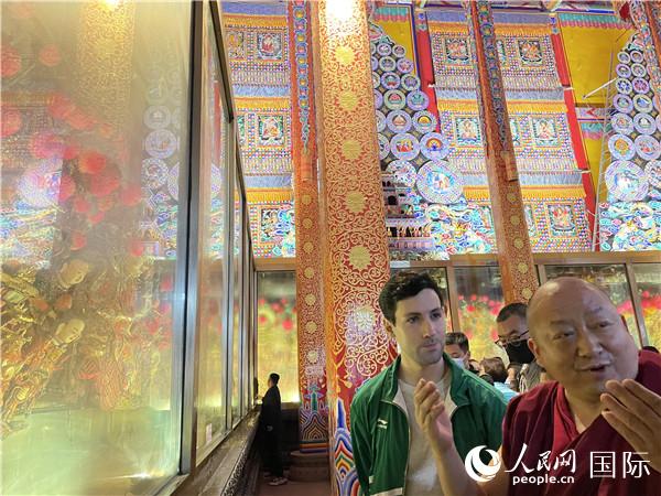 7月25日，省級非物質(zhì)文化遺產(chǎn)項目塔爾寺酥油花的代表性傳承人朋措堅參（右）在塔爾寺酥油花館講解酥油花的制作過程。人民網(wǎng) 謝瑩攝