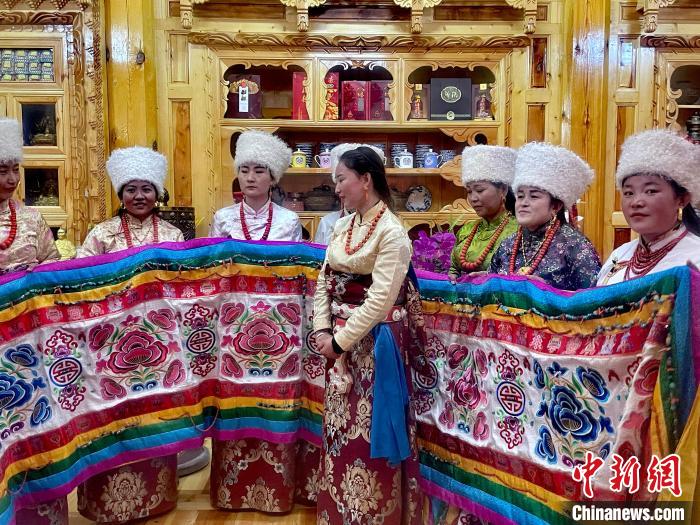 圖為女性展示村民自發(fā)繡制的“百米五彩哈達(dá)”?！±钣穹?攝