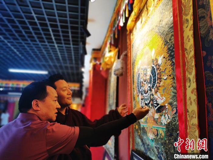 圖為久美尖措展示唐卡作品?！?zhí)砀?攝