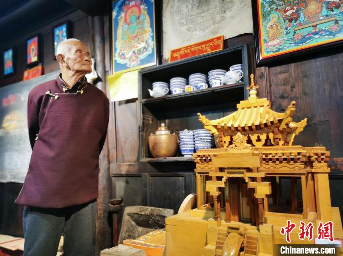 圖為古堡內(nèi)的藝人桑杰展示自己的雕刻作品?！?zhí)砀?攝