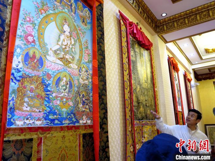 圖為完德尖措展示熱貢龍樹(shù)畫(huà)苑內(nèi)的唐卡。　張?zhí)砀?攝