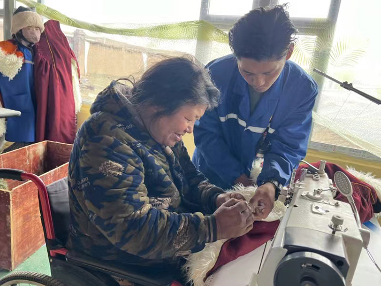 扎西奪爾登幫助殘疾員工裁剪。阿壩州文明辦供圖