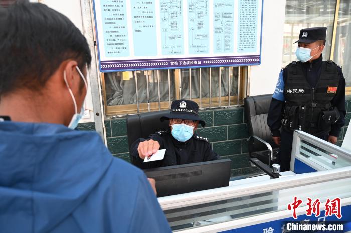 圖為移民管理警察登記完身份信息后將證件歸還給行人?！≮w朗 攝