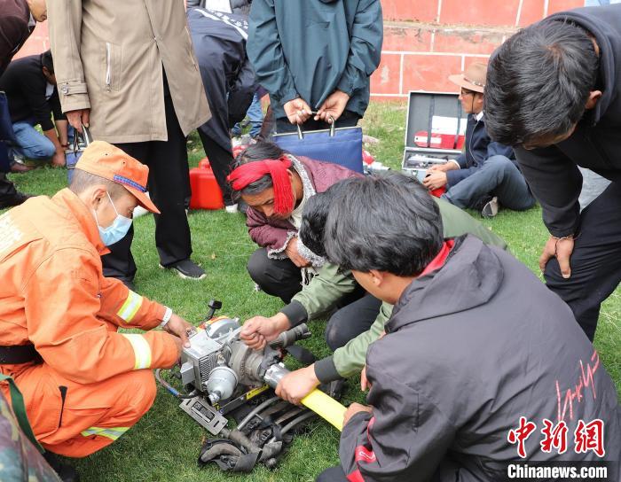 圖為森林消防員為護(hù)林員講解滅火裝備的使用方法?！〔际猩窒乐ш?duì) 供圖