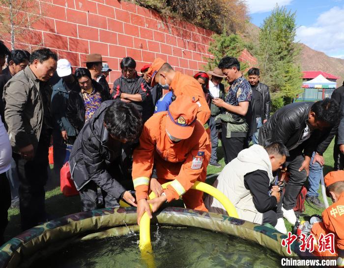 圖為森林消防員為護(hù)林員講解滅火裝備的使用方法?！〔际猩窒乐ш?duì) 供圖