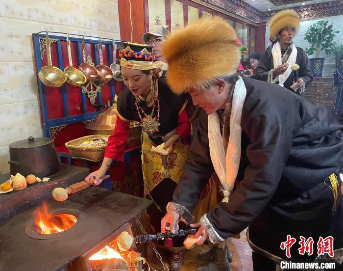 圖為人們在火上烤節(jié)日美食“結(jié)達(dá)”?！∪轿木?攝