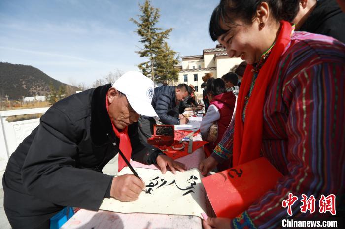 圖為林芝市文聯(lián)書法家協(xié)會(huì)會(huì)員向民眾贈(zèng)送藏文書法作品?！埩?攝