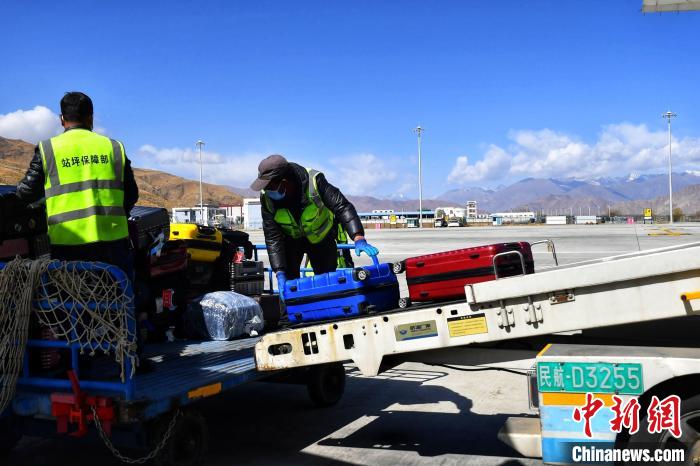 圖為機場工作人員傳送旅客行李箱?！≈芎?攝