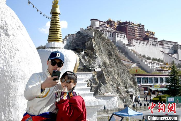4月17日，游客身著藏式元素服裝在拉薩布達(dá)拉宮觀景臺(tái)拍照留念。　李林 攝
