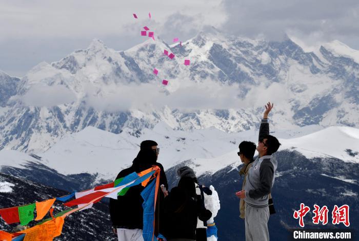 圖為5月14日，游客在西藏林芝色季拉山觀景臺(tái)拋灑“隆達(dá)”(風(fēng)馬旗，藏族民眾的一種祈福方式)?！±盍?攝